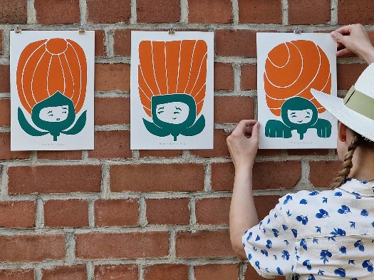 Drei gerahmte Blume mit Gesicht in Grün mit je einer Blüte in Orange auf weißem Papier