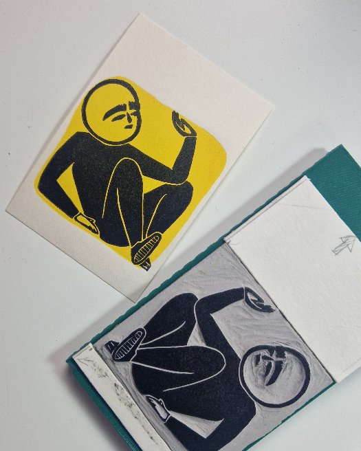 Stilisierte Person in Schwarz mit angezogenen Armen und Beinen vor einem gelben Hintergrund, gedruckt auf weißem Papier